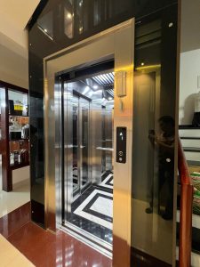 Thang máy kính khung thép Bắc Giang tại nhà chị Hạnh, 168 Nguyễn Khuyến — cabin inox xước, cửa mở nhìn vào sàn đá hoa văn