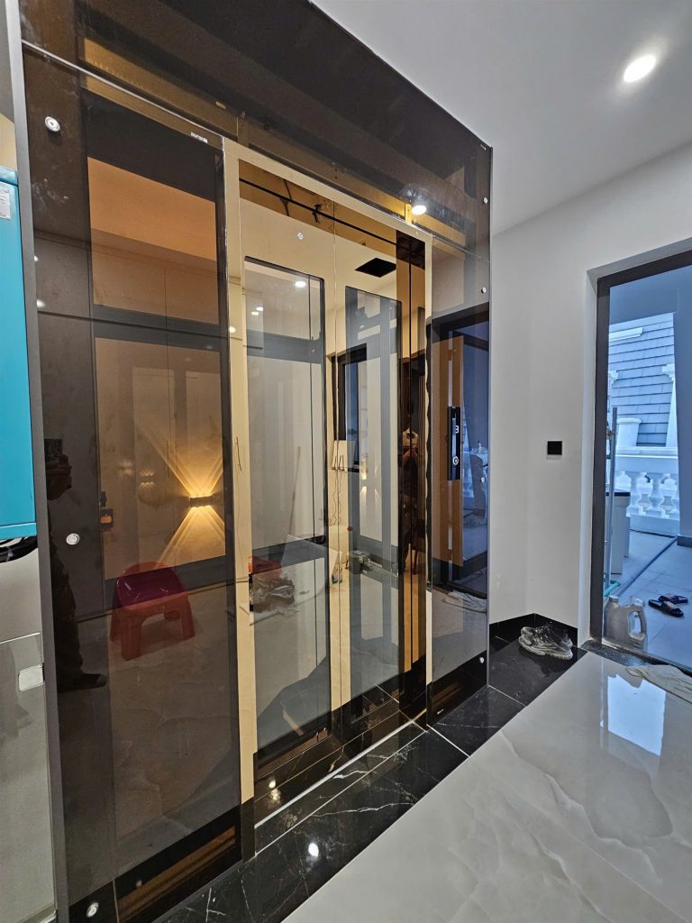 Hố thang kính khung inox vàng hồng gương nhìn từ sảnh tầng một nhà anh Tuấn Vincom Bắc Giang
