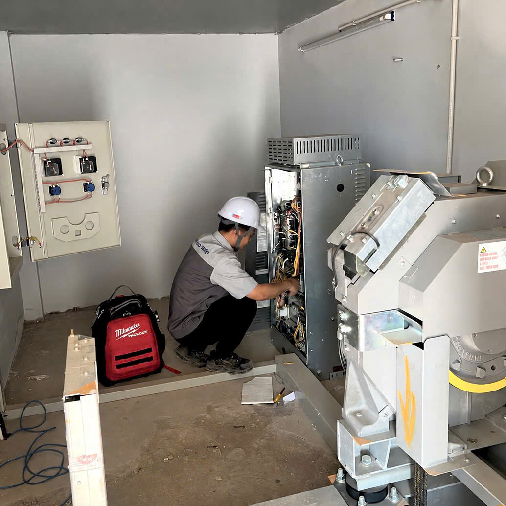 Kỹ thuật viên mở tủ điều khiển thang máy trong phòng máy khi bảo trì định kỳ tại trường học ở Bắc Giang